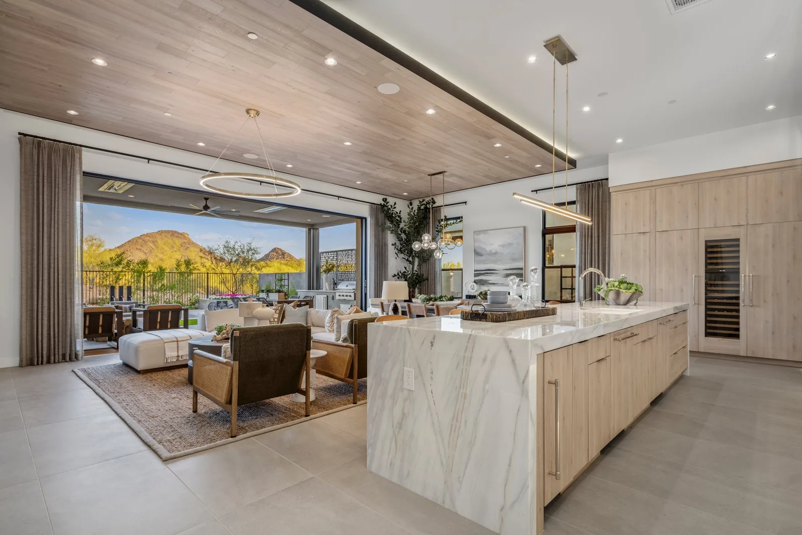 Model-home kitchen and living area opening toward a terrace and desert mountain view
