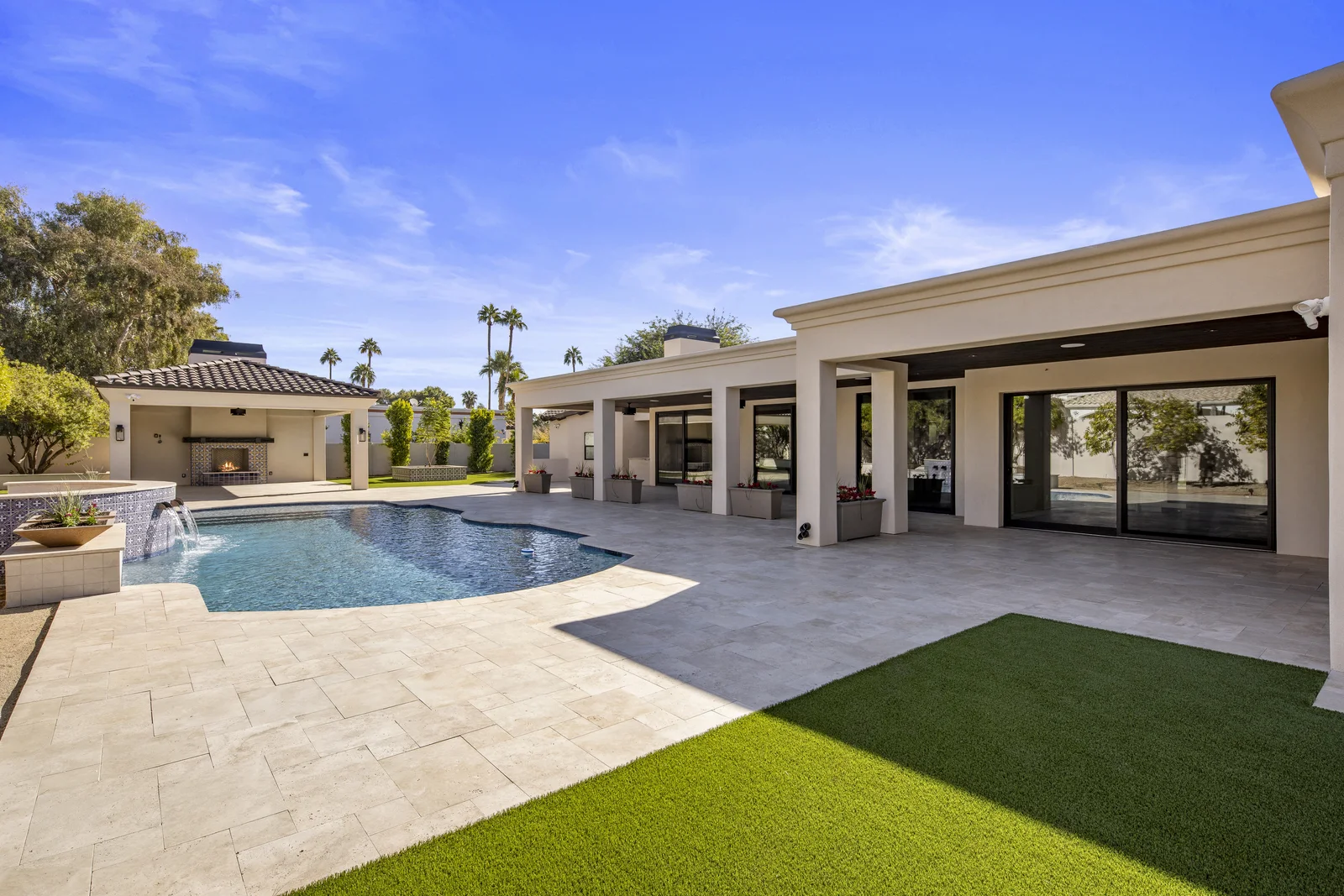 Poolside courtyard with a covered patio and landscaped lawn at a desert residence