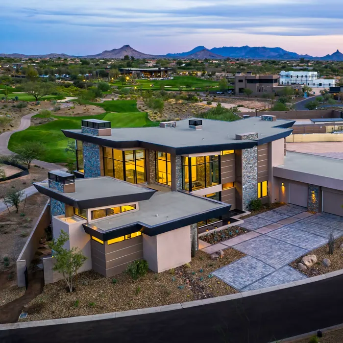 Aerial view of a contemporary desert residence among landscaped lots at dusk