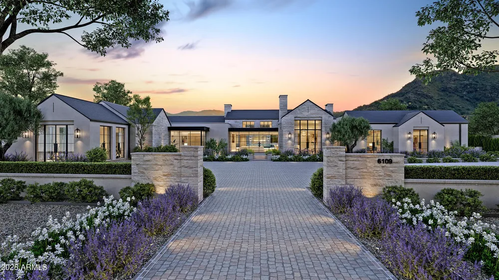 Modern residence behind a landscaped stone entry at sunset