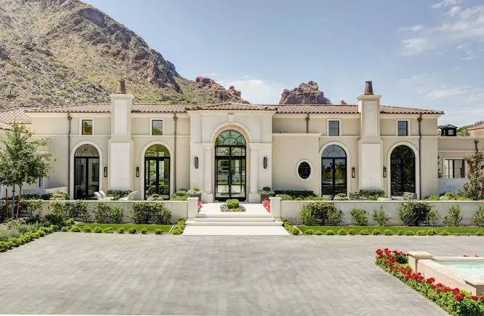 Light-colored home with arched windows and a mountain backdrop