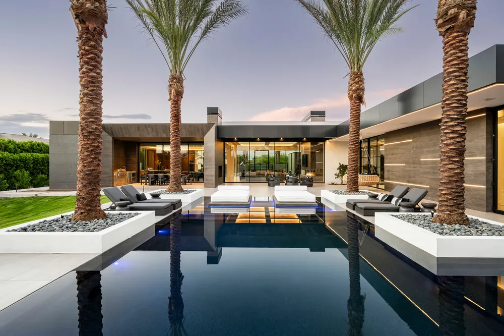 Outdoor living terrace beside a reflecting pool, framed by palms and contemporary architecture