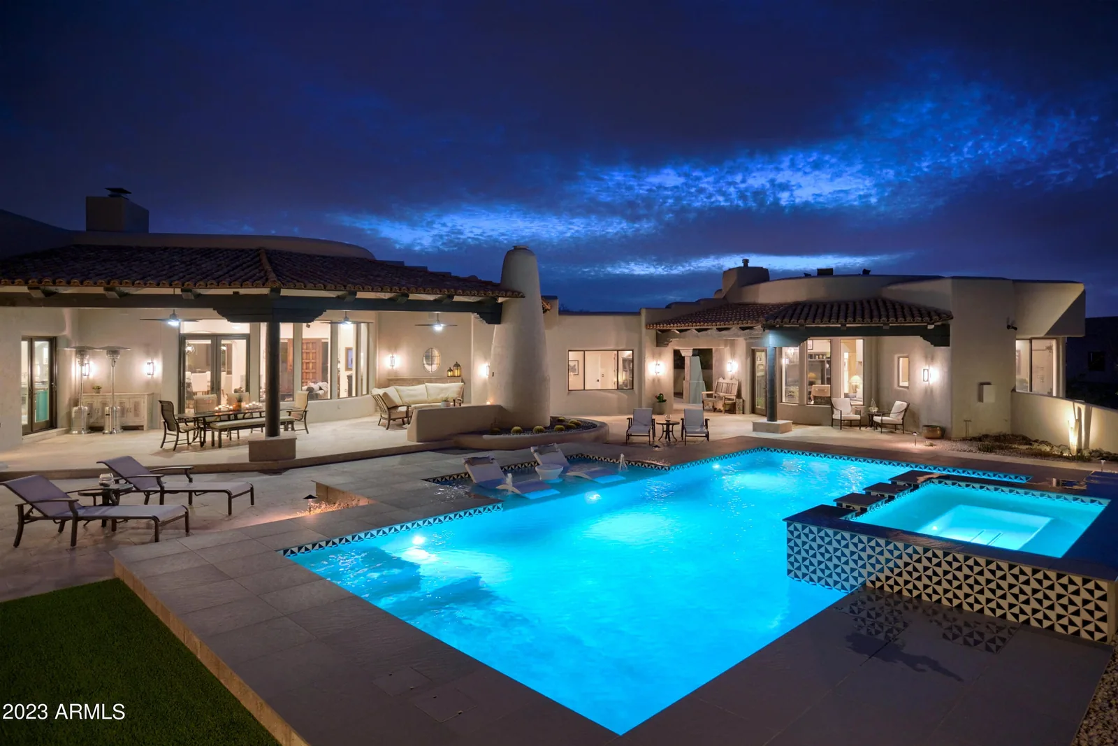 Desert residence with an illuminated swimming pool and outdoor lounge at twilight
