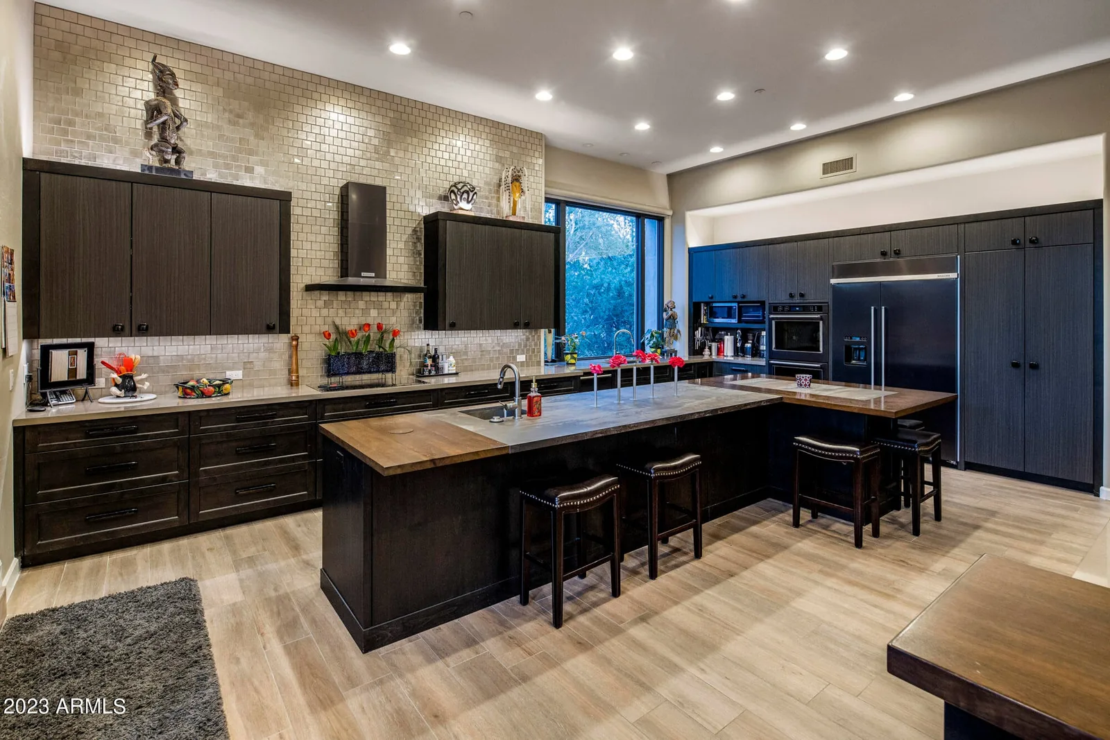 Kitchen with dark cabinetry, tile backsplash, and a large center island