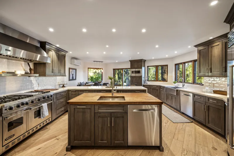 Remodeled kitchen with a wood-topped island, dark cabinetry, professional range and stainless appliances