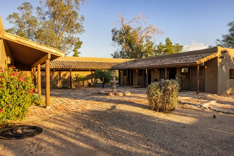 Gravel courtyard framed by low southwestern buildings with covered porches and flowering shrubs