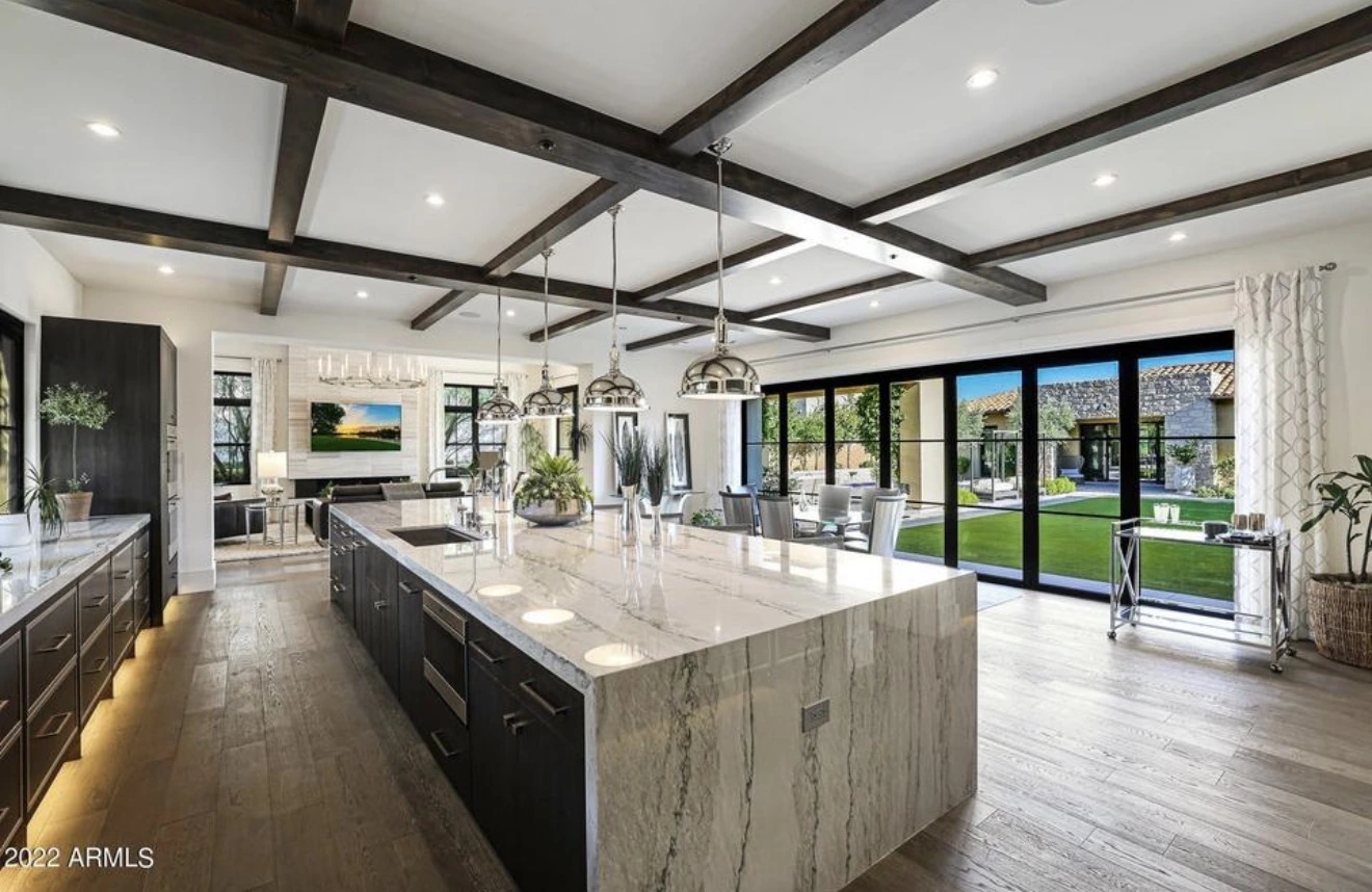 Open kitchen with a large marble island and garden-facing glass doors