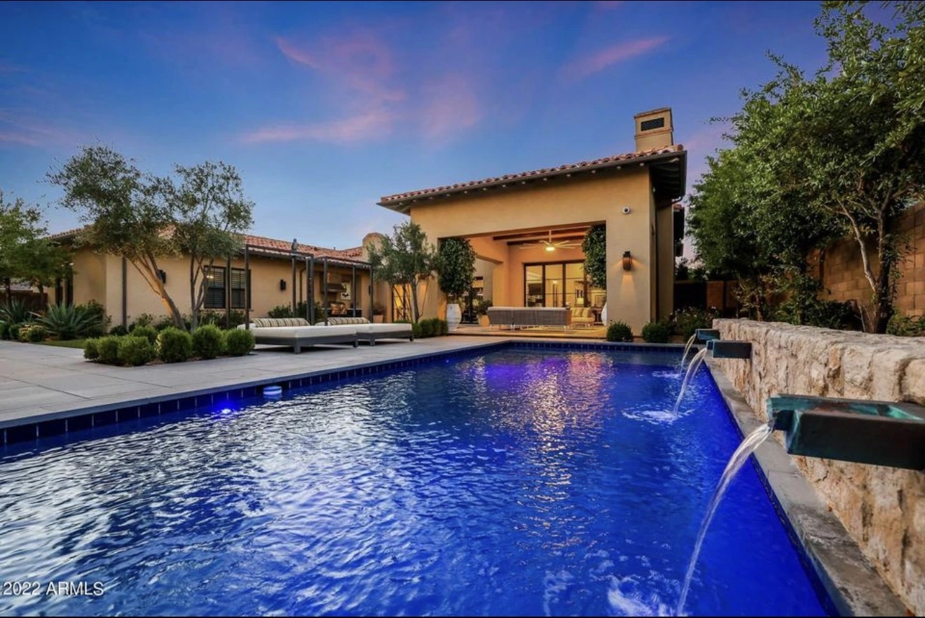 Desert home and illuminated swimming pool at twilight